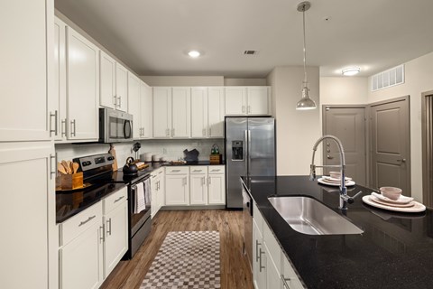 A modern kitchen with white cabinets and black countertops.