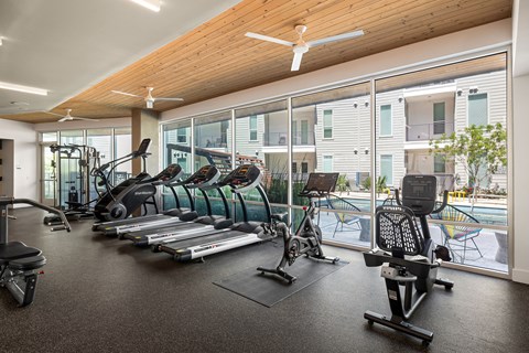 A gym with a variety of equipment including treadmills, elliptical machines, and weights.