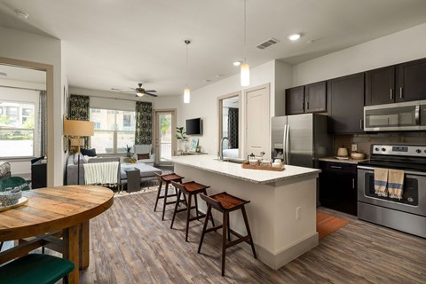 A modern kitchen with a wooden table and bar stools.