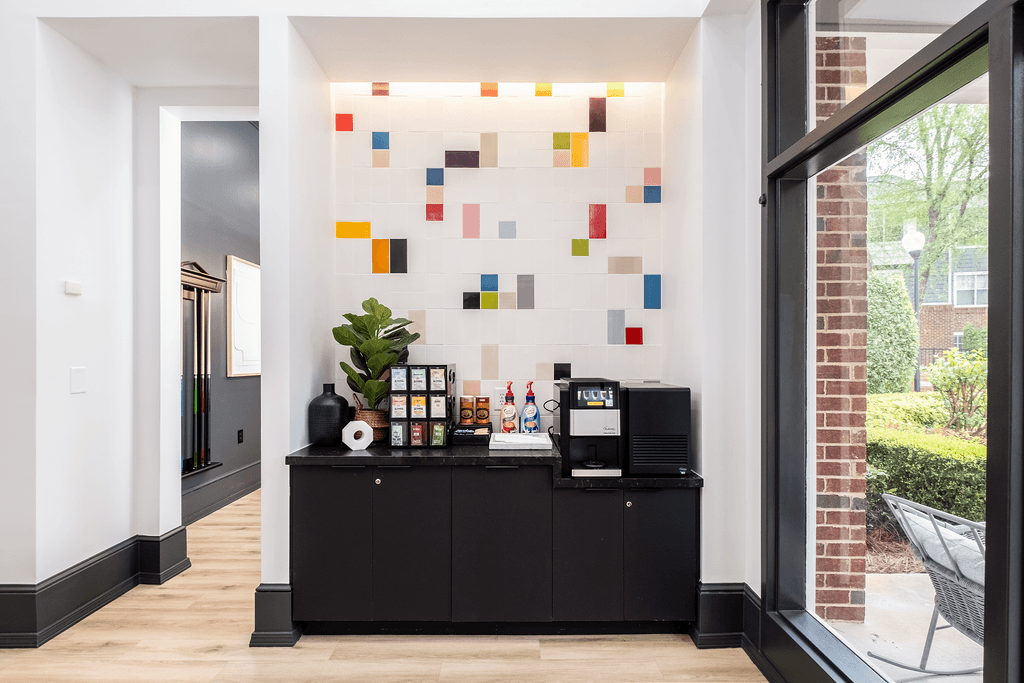 a lobby with a black bar and a coffee machine and a colorful wall with tiles
