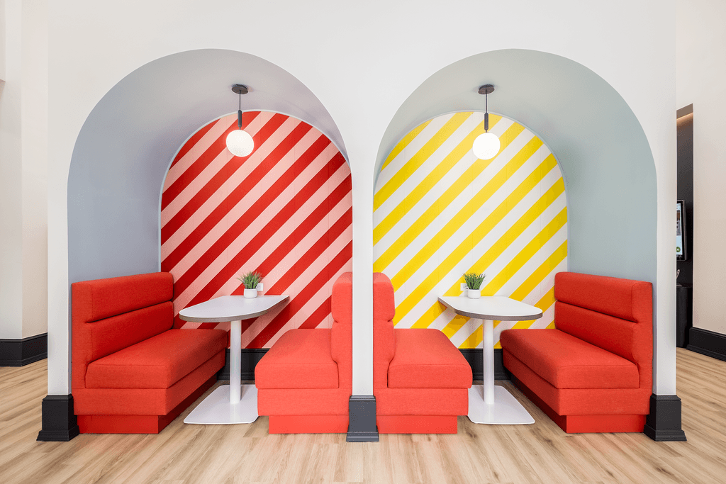 two orange chairs and tables in a room with two surfboards