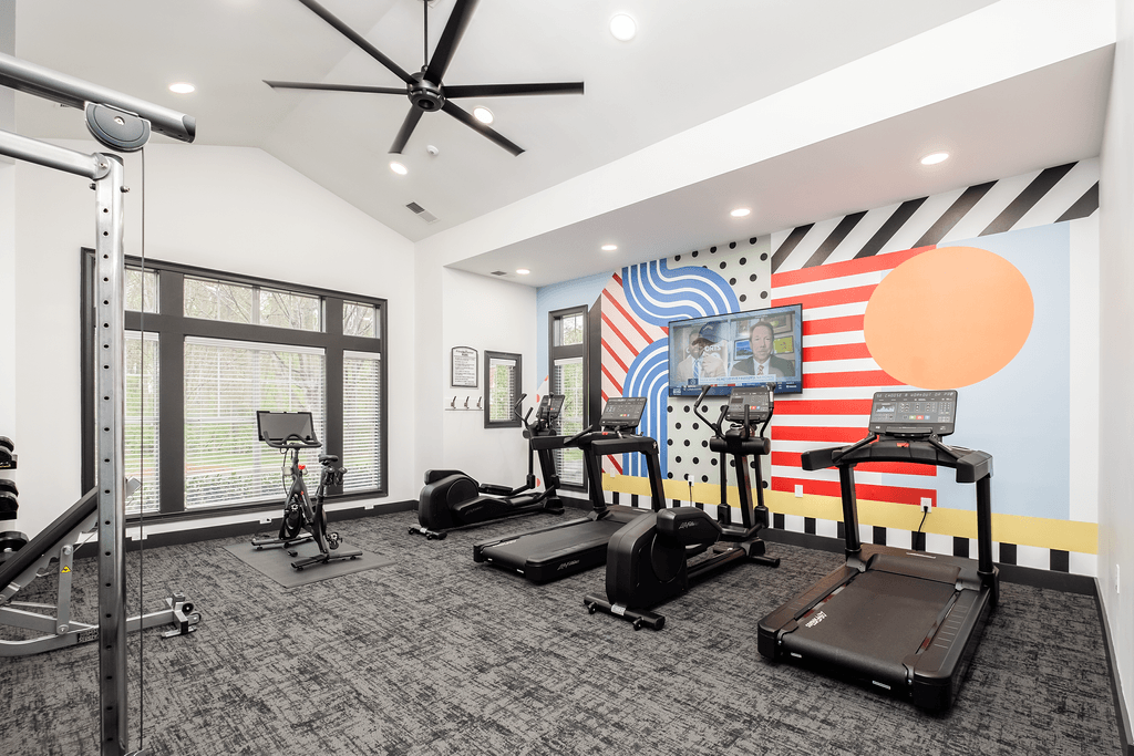 a fitness room with treadmills and weights and a large window