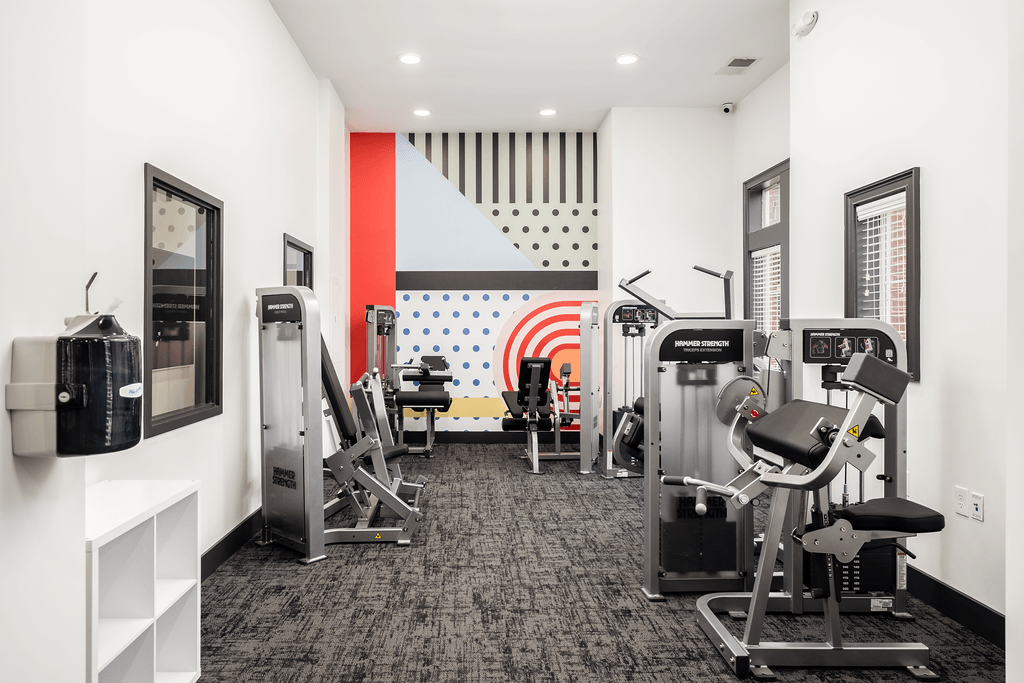 a gym with cardio machines and other exercise equipment in a room with white walls