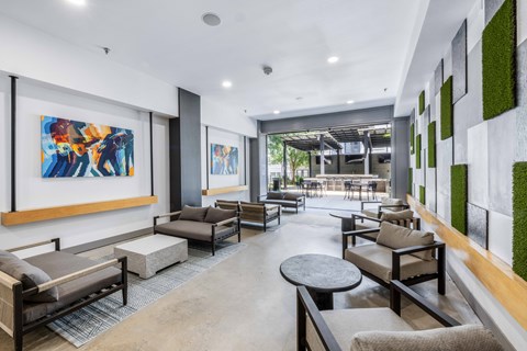 A modern living room with a large painting on the wall and a green plant on the side.