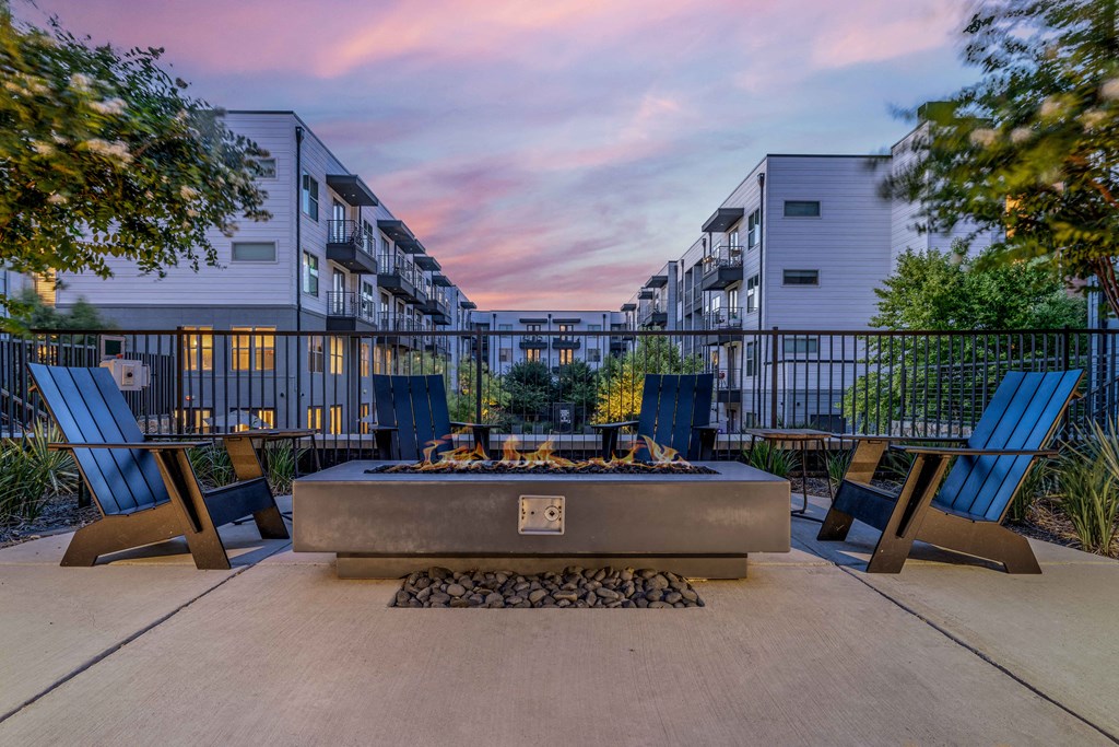 an outdoor patio with a fire pit and chairs at dusk