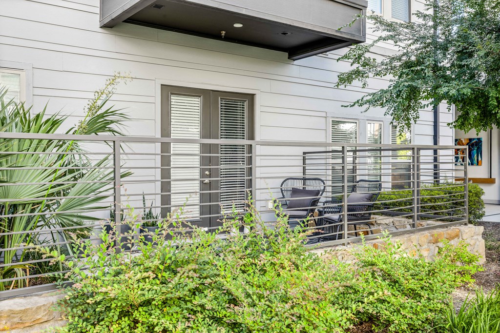 a patio with chairs and a fence in front of a house