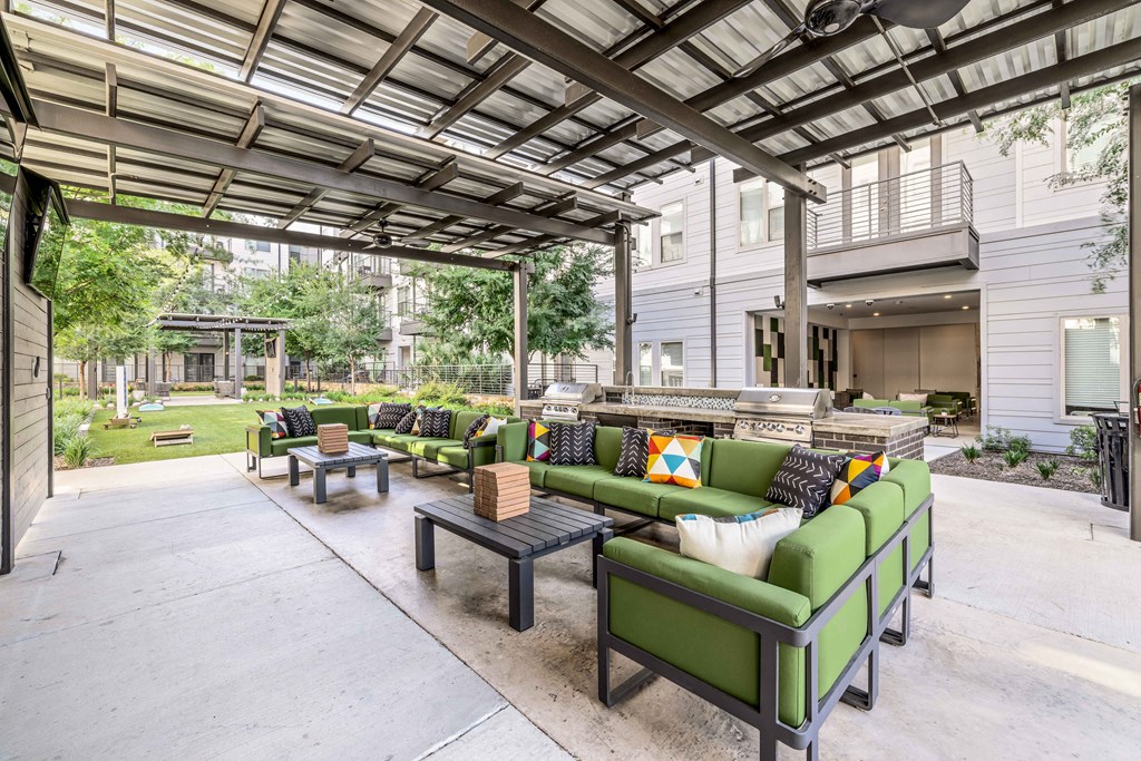 a patio with green couches and tables and a building in the background