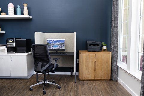 A black office chair is in front of a desk with a computer.