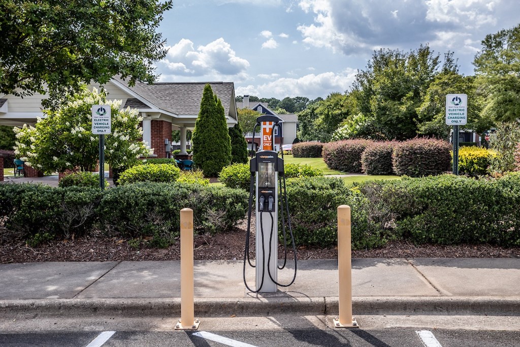 a gas pump in a parking lot with a house in the background