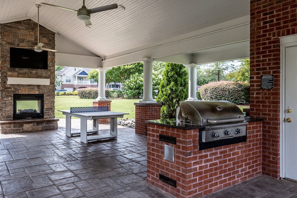 a covered patio with a fireplace and a barbecue
