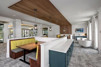 A modern restaurant interior with a wooden ceiling and grey carpet.