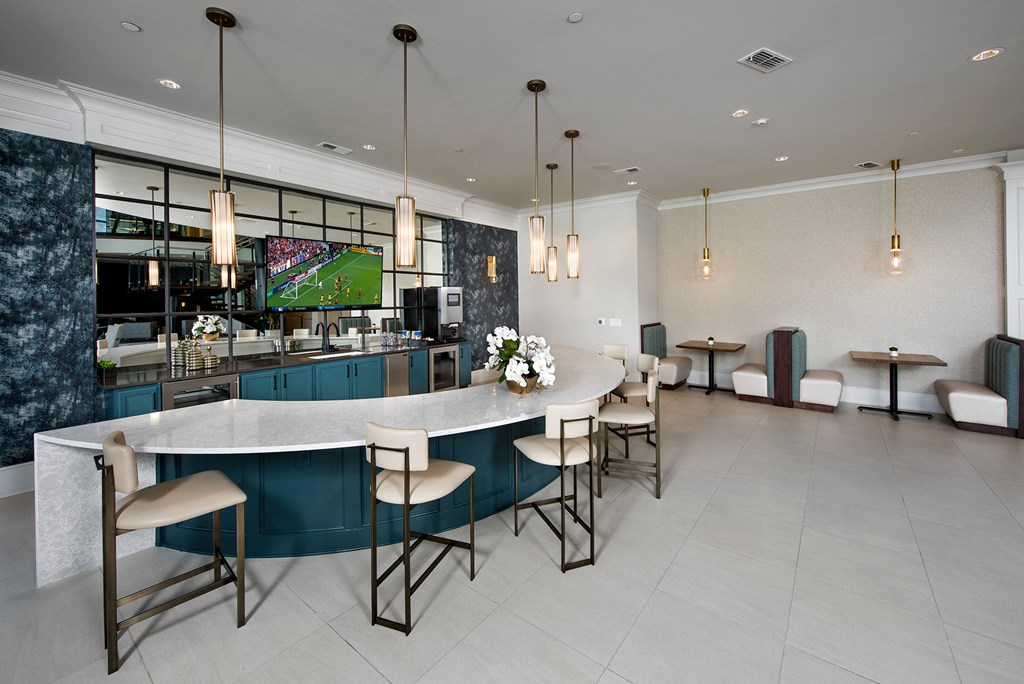 the lobby of a hotel with a large bar with chairs and a television