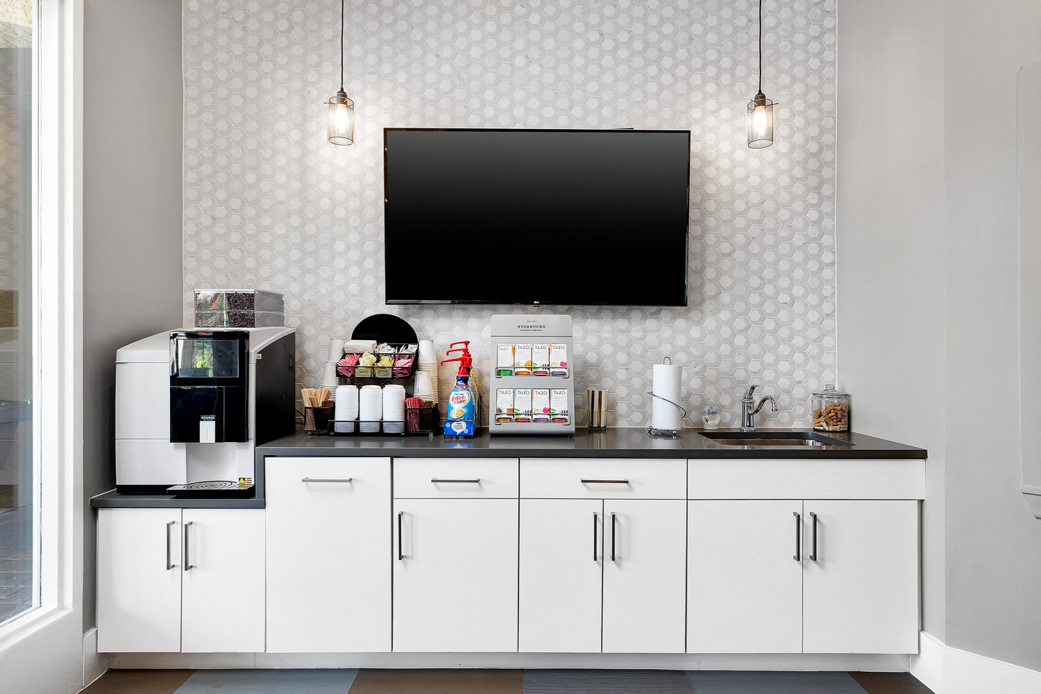 a white kitchen with a coffee machine and a tv on the wall