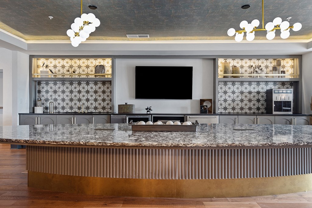 A modern bar with a dark counter top and a television mounted on the wall.