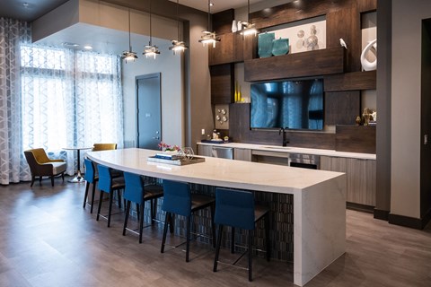a kitchen with a long white counter top and blue chairs