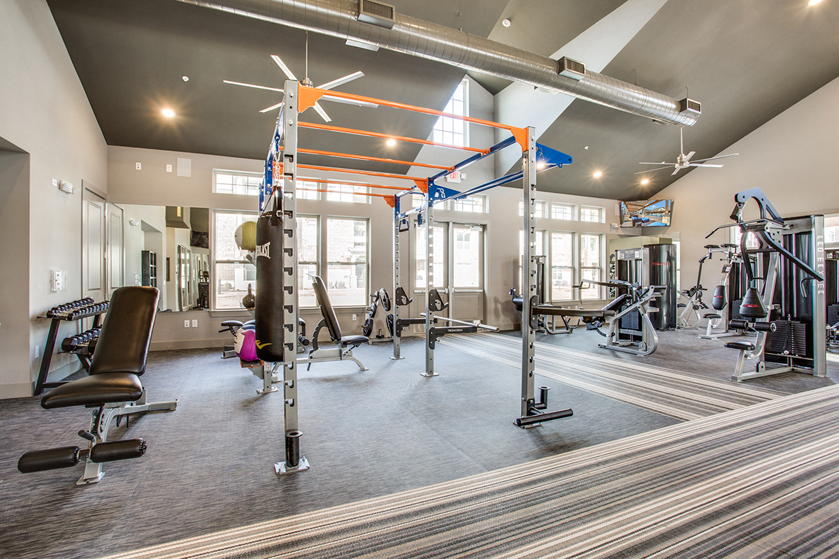 a gym with weights and exercise equipment at the district at highland village apartments