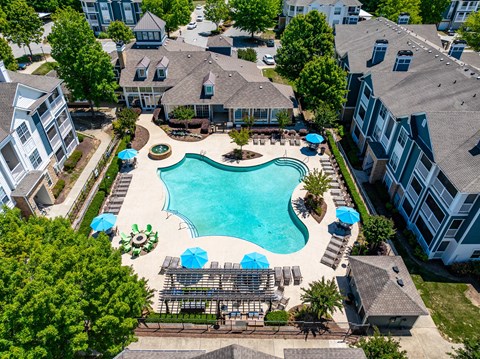 An aerial view of a swimming pool surrounded by buildings and trees.