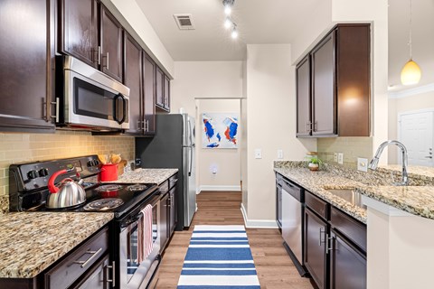 A kitchen with dark brown cabinets and granite countertops.