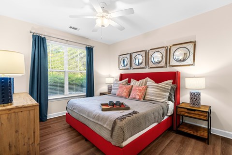 A bedroom with a bed, nightstand, and a window with blue curtains.