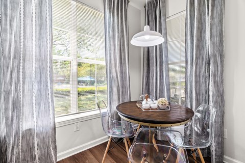 A dining room with a table set for two and a view of a backyard.