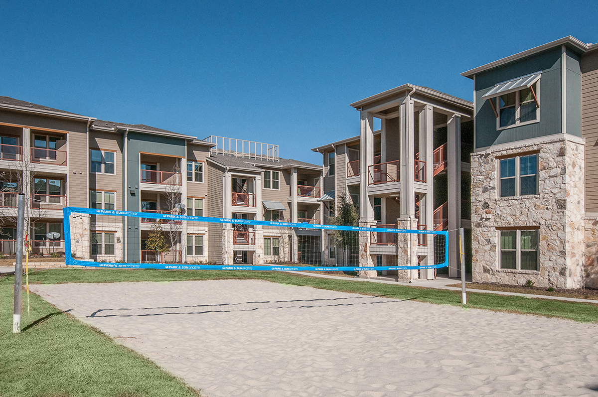 an outdoor court with a volleyball court in front of an apartment building