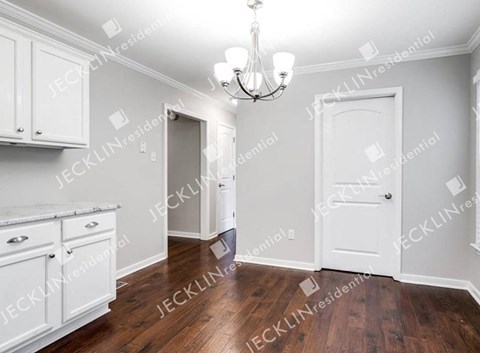 A well-lit, spacious room with wooden floors and white cabinetry.