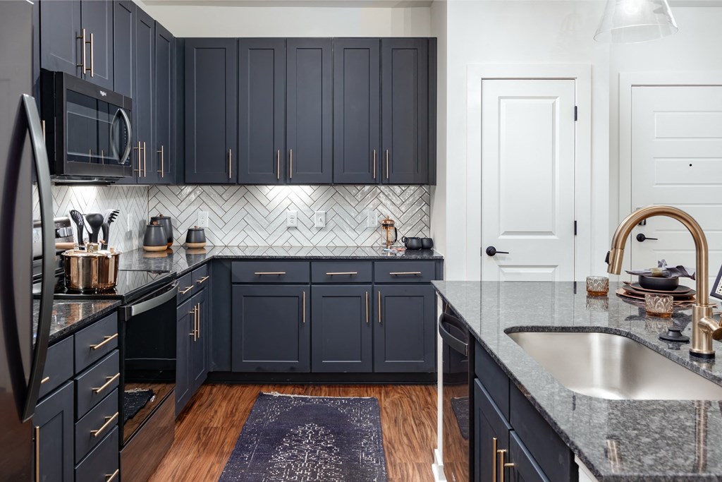 a kitchen with dark blue cabinets and a counter top and a sink