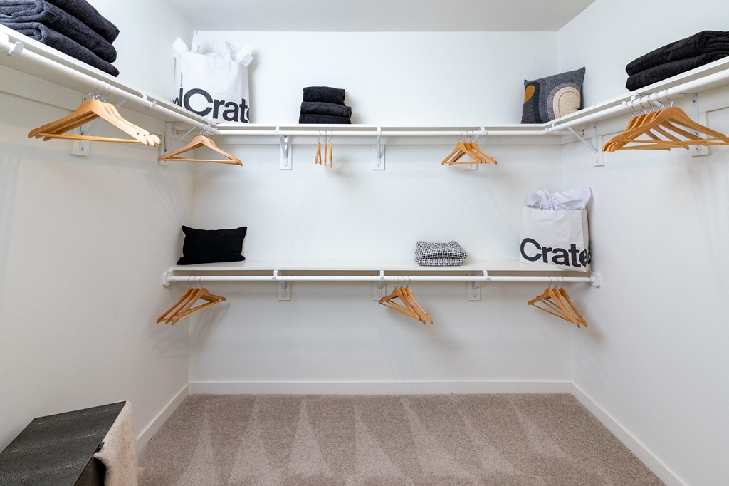 a walk in closet with white walls and shelves and a bench