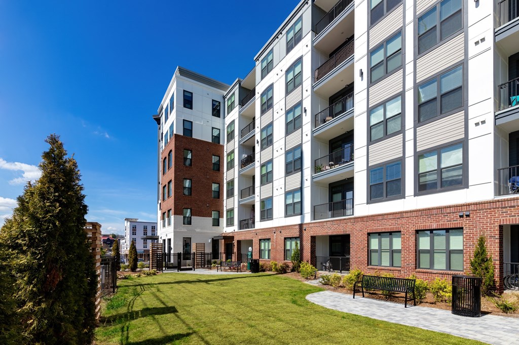 an exterior view of an apartment building with a courtyard and lawn