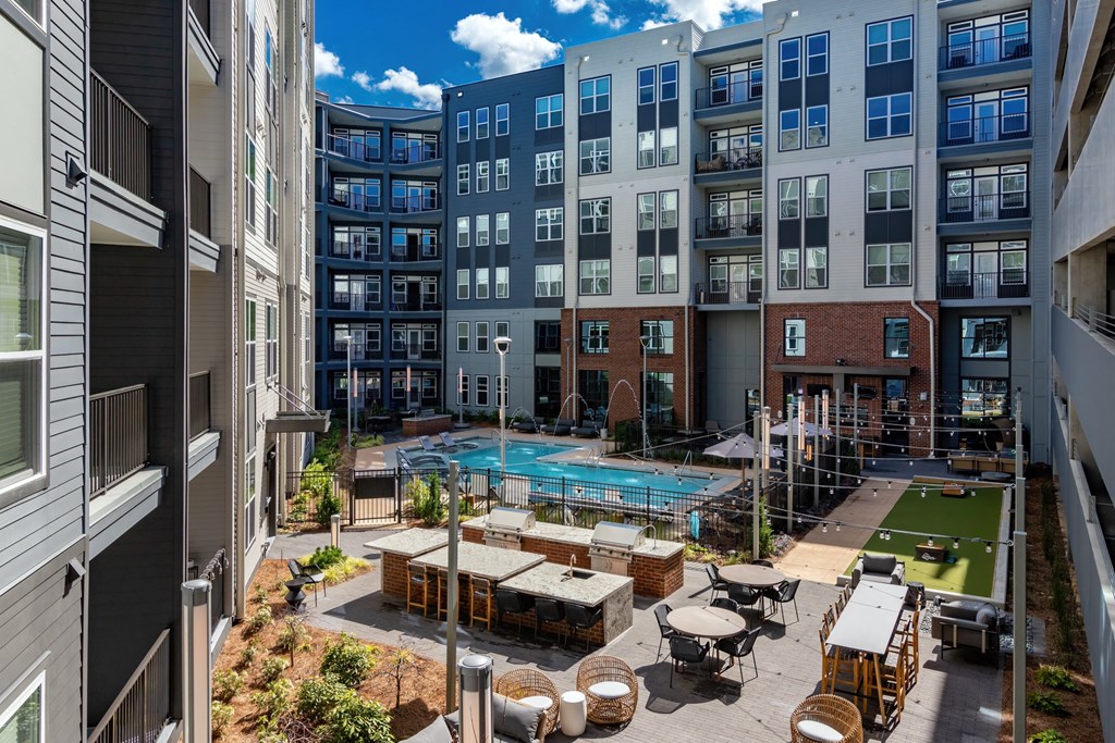an open courtyard with a pool and tables in front of an apartment building