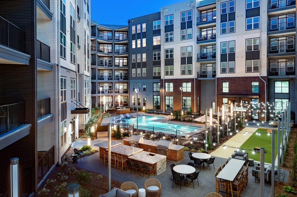 an apartment building with a pool and tables in the middle