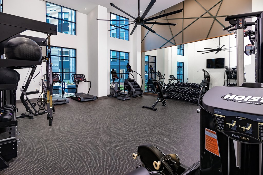 a gym with cardio equipment and weights in a building with windows