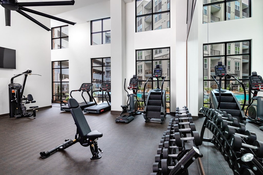 a gym with cardio equipment and windows in a building