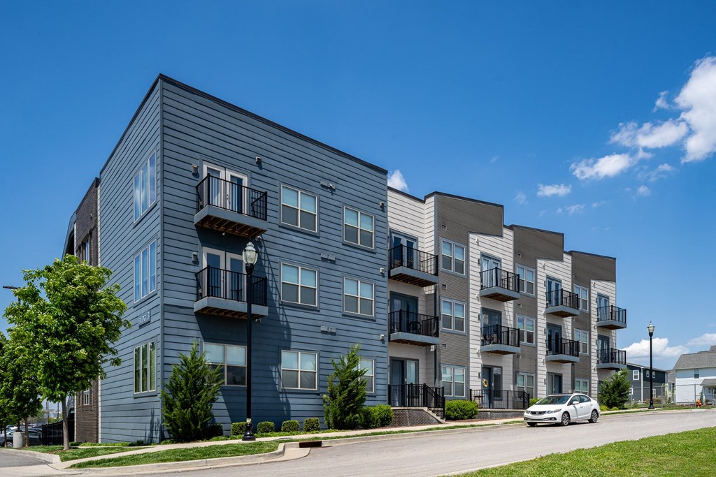 an apartment building on a city street with a white car