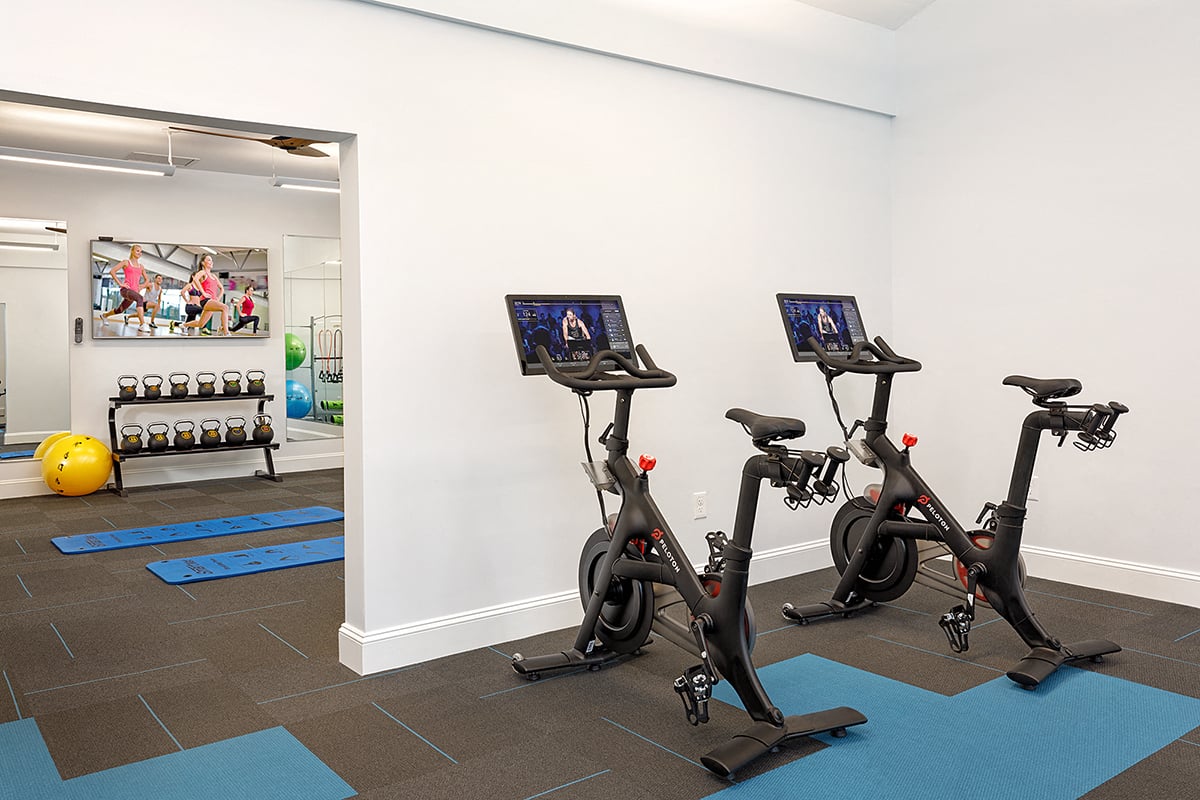 a gym with exercise bikes and weights in a room with a mirror