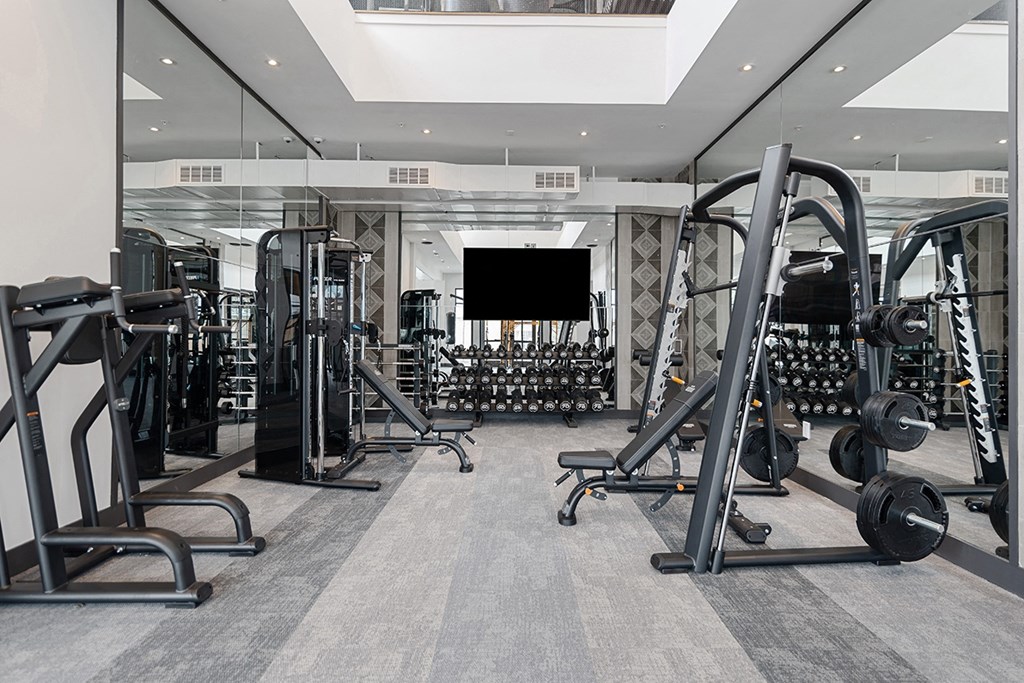 A gym with a variety of equipment including treadmills, weights, and exercise machines.