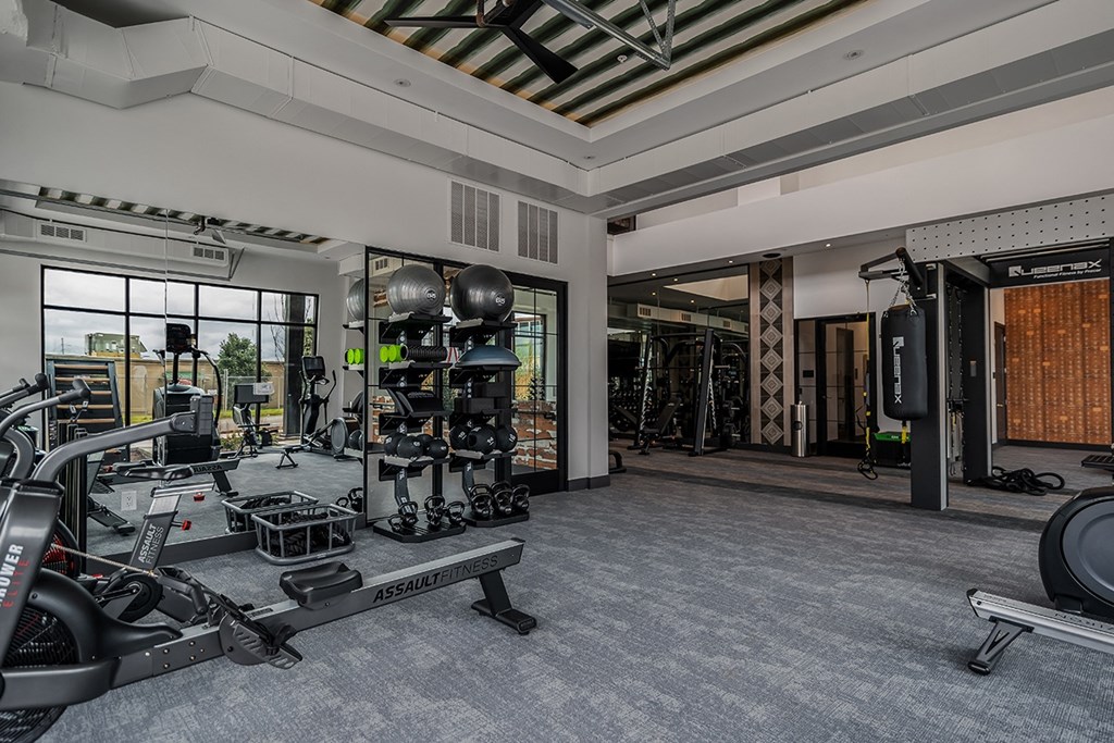 A spacious gym with a variety of equipment including a treadmill, a stationary bike, and a rowing machine.