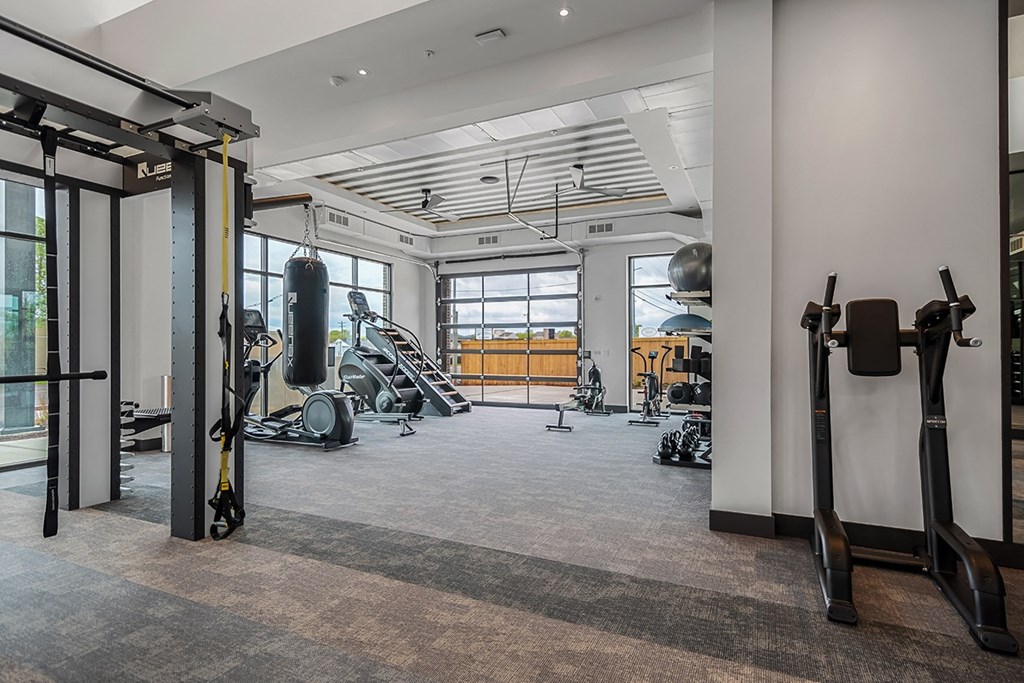 A gym with a variety of equipment including a punching bag, treadmill, and weight machines.