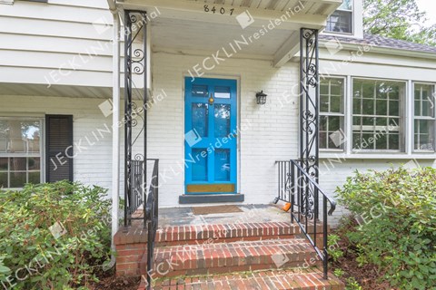 A white house with a blue door and a black gate.