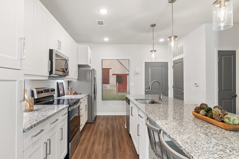 A kitchen with white cabinets and a granite countertop.