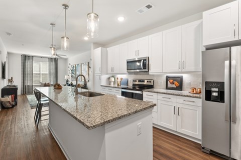 A modern kitchen with a granite countertop and stainless steel appliances.