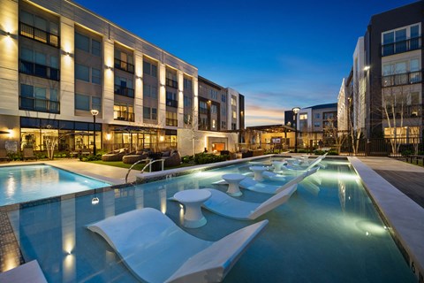a large pool with lounge chairs in front of a building