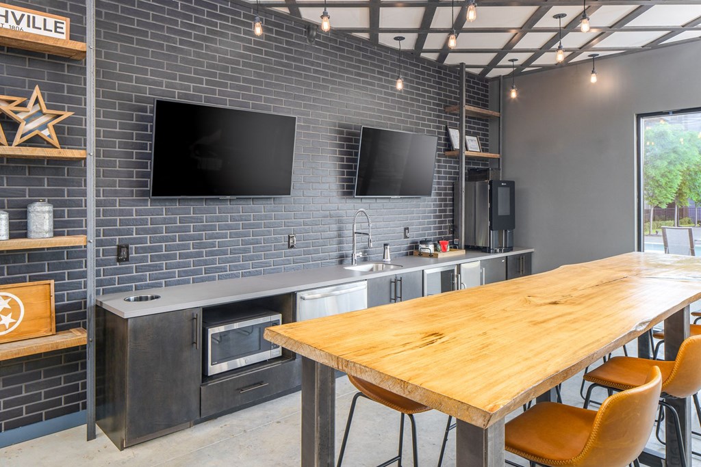 a kitchen with a wooden table and two televisions