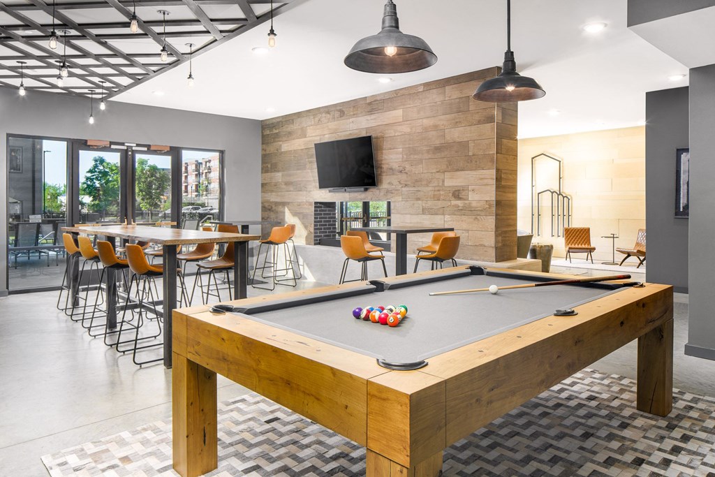 a pool table in a clubhouse with a bar and a tv