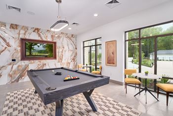 A pool table in a room with a marble wall and a painting of a landscape.
