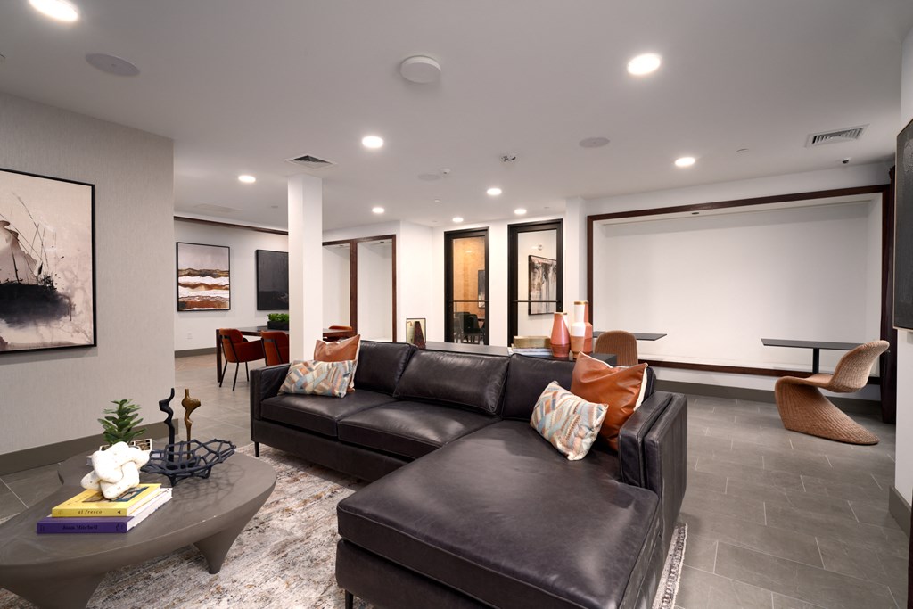 A living room with a black couch and a grey coffee table.