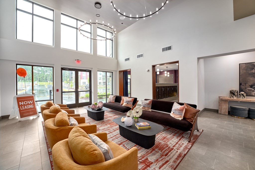 A living room with a long couch and a sign that says "Now Leasing".