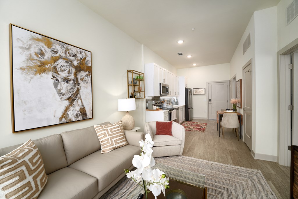 A living room with a large painting on the wall and a beige couch.