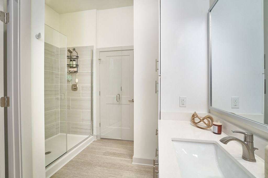 A bathroom with a white sink, mirror, and tiled shower.