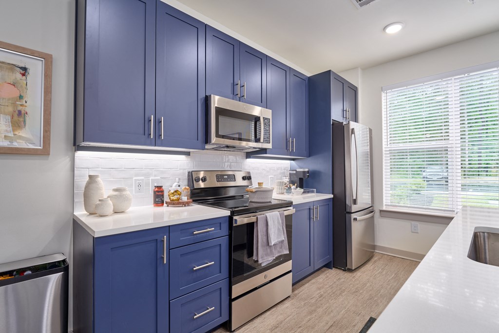 A kitchen with blue cabinets and stainless steel appliances.